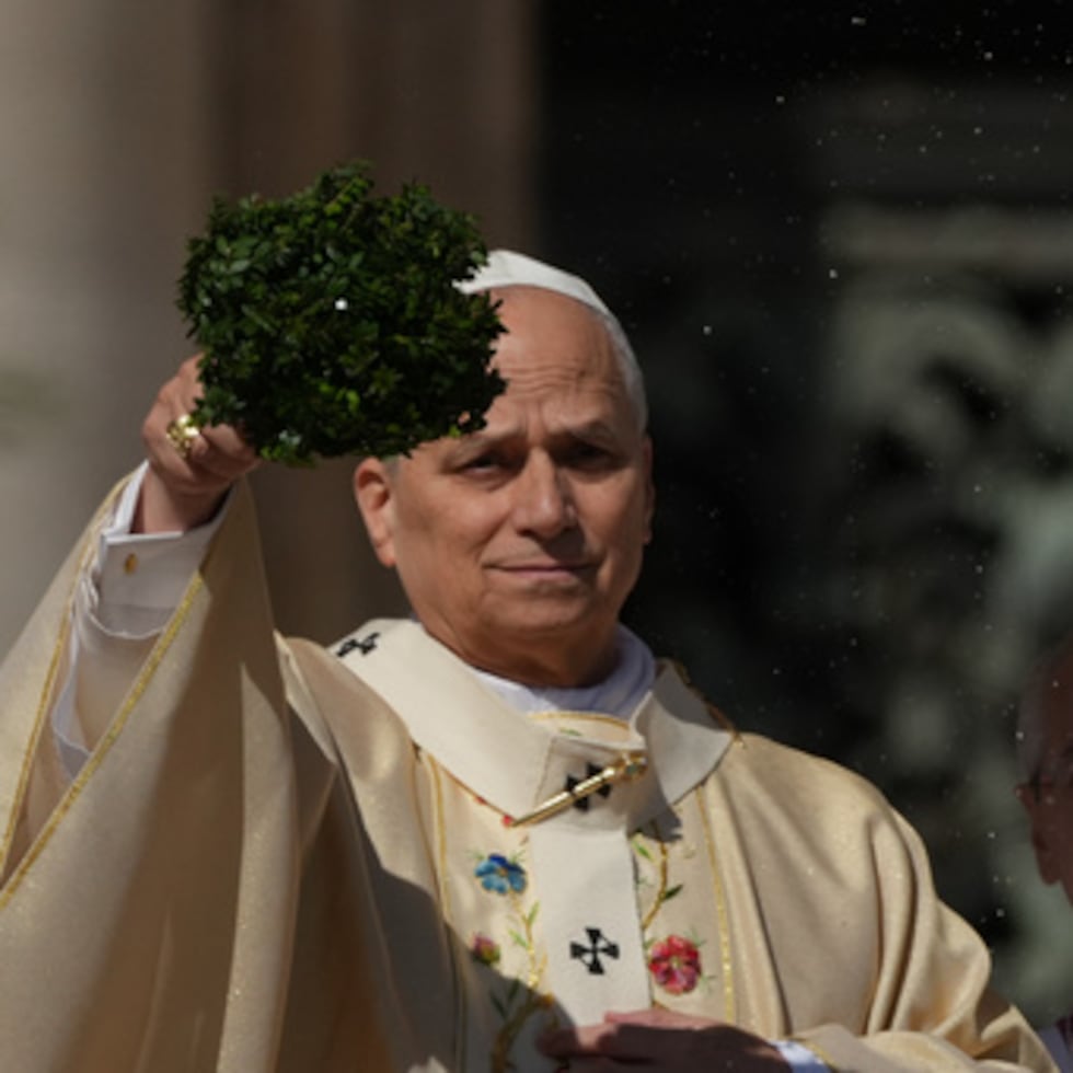 El papa León XIV rocía agua bendita con un manojo de ramas de hisopo mientras preside la ,isa de Pascua en la plaza de San Pedro del Vaticano.