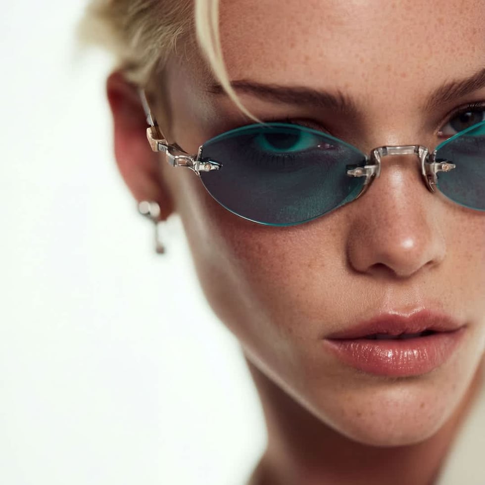 Las gafas ovaladas con lentes tintadas y sin montura reflejan la estética minimalista de los años 90 con una silueta depurada, convirtiéndolas en una opción discreta pero con mucha intención estilística