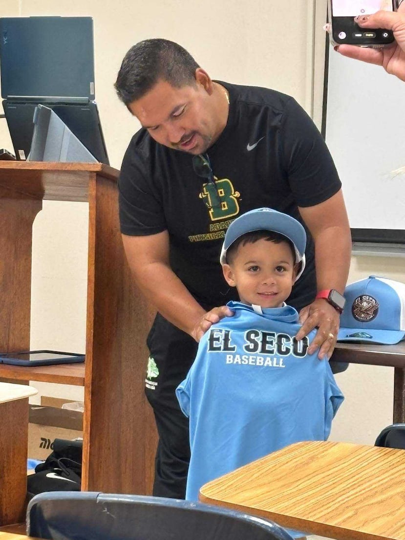El profesor del Departamento de Kinesiología de la UPR en Mayagüez, Dr. Christian Martínez Rivera, entregando un uniforme a un niño de otro de los programas infantiles en la comunidad El Seco.