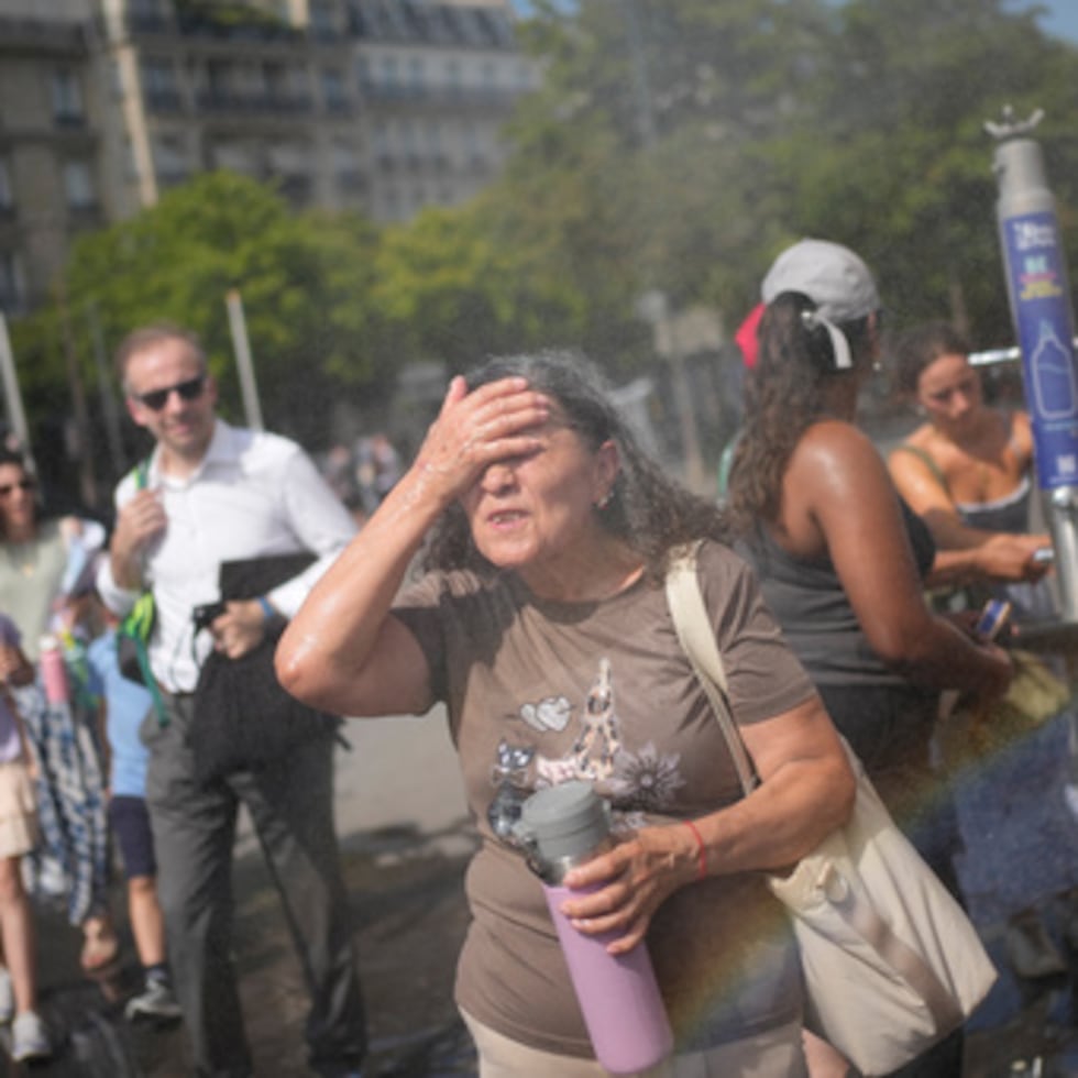 Los turistas disfrutan refrescándose en una fuente pública de París, el viernes 26 de junio de 2026. (Foto AP/Christophe Ena)
