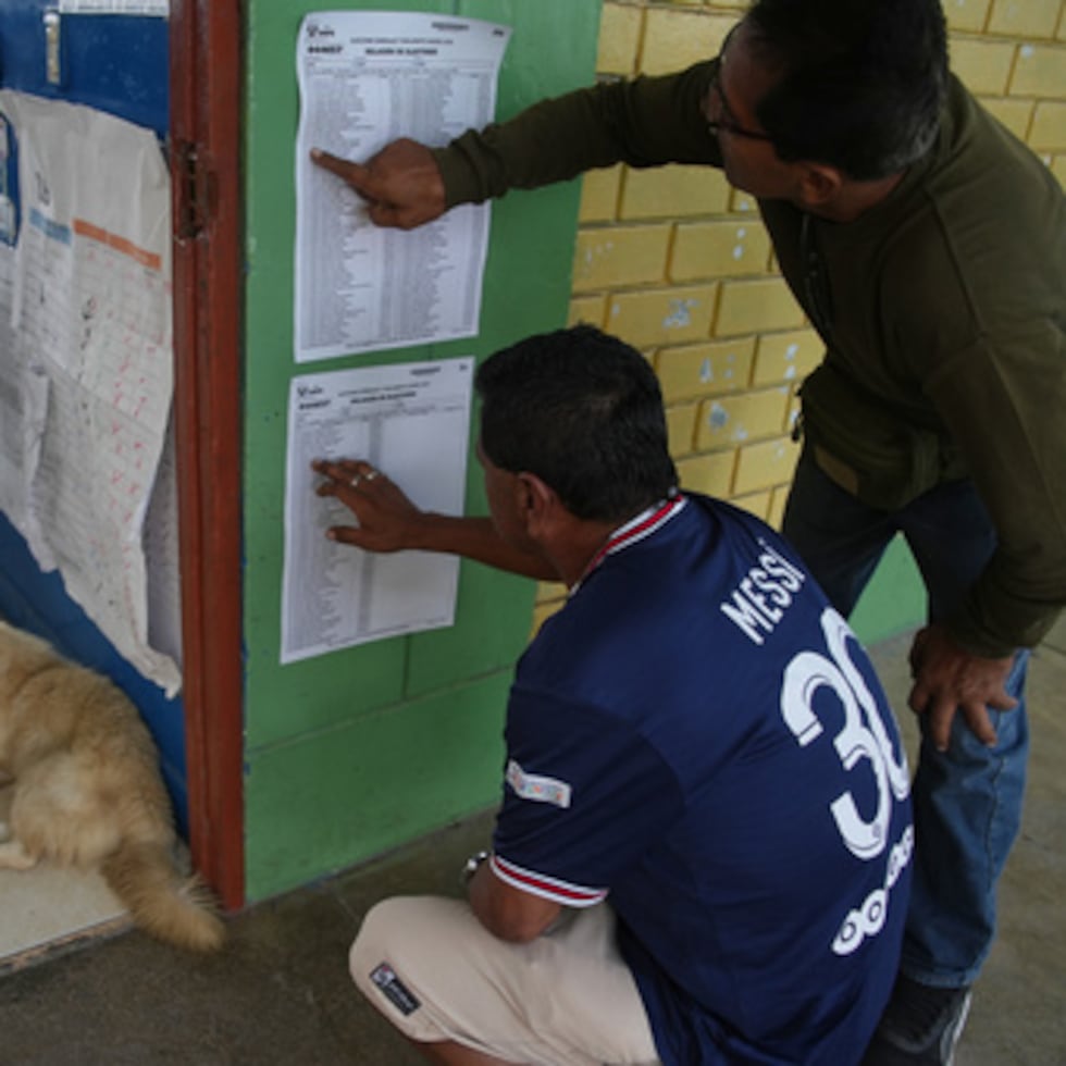 Votantes revisan las listas mientras se reanuda la votación de las elecciones generales en los colegios electorales afectados por retrasos y problemas logísticos.