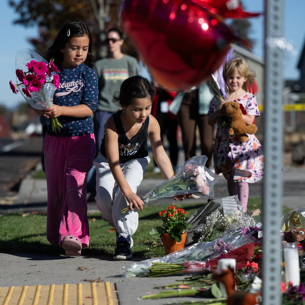 Niños colocando flores frente a la escuela Silver Rail, donde un adolescente de 16 años asesinó a cuatro personas.