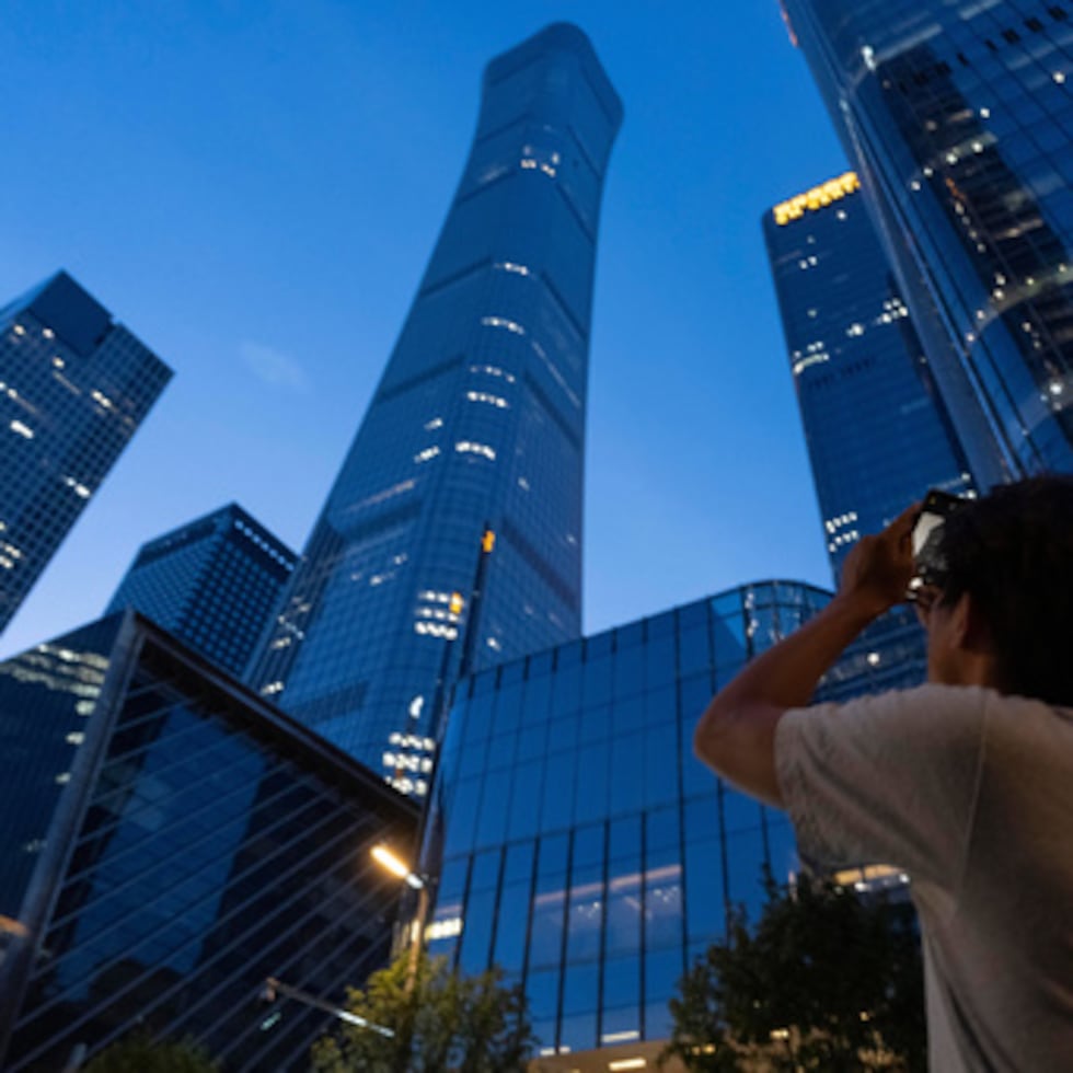 Un transeúnte intenta hacer una foto de los daños sufridos por la Torre Citic, también conocida como Torre Zun, en Pekín.