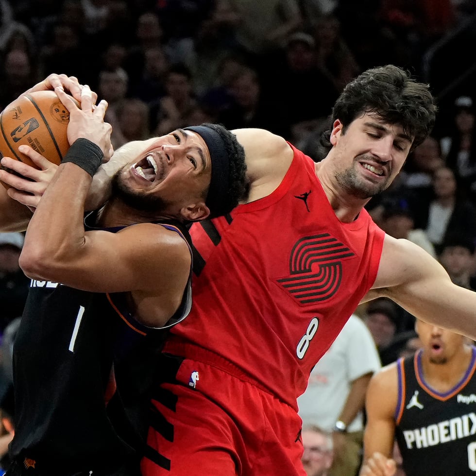 Devin Booker y Deni Avdija luchan por el balón en el juego del martes en Phoenix.