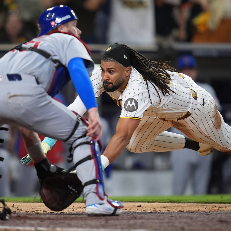 Fernando Tatis, Jr. se lanza de cabeza en el plato por los Padres, ante el receptor Carson Kelly, de los Cubs, en la séptima entrada del primer juego de la serie de comodines.