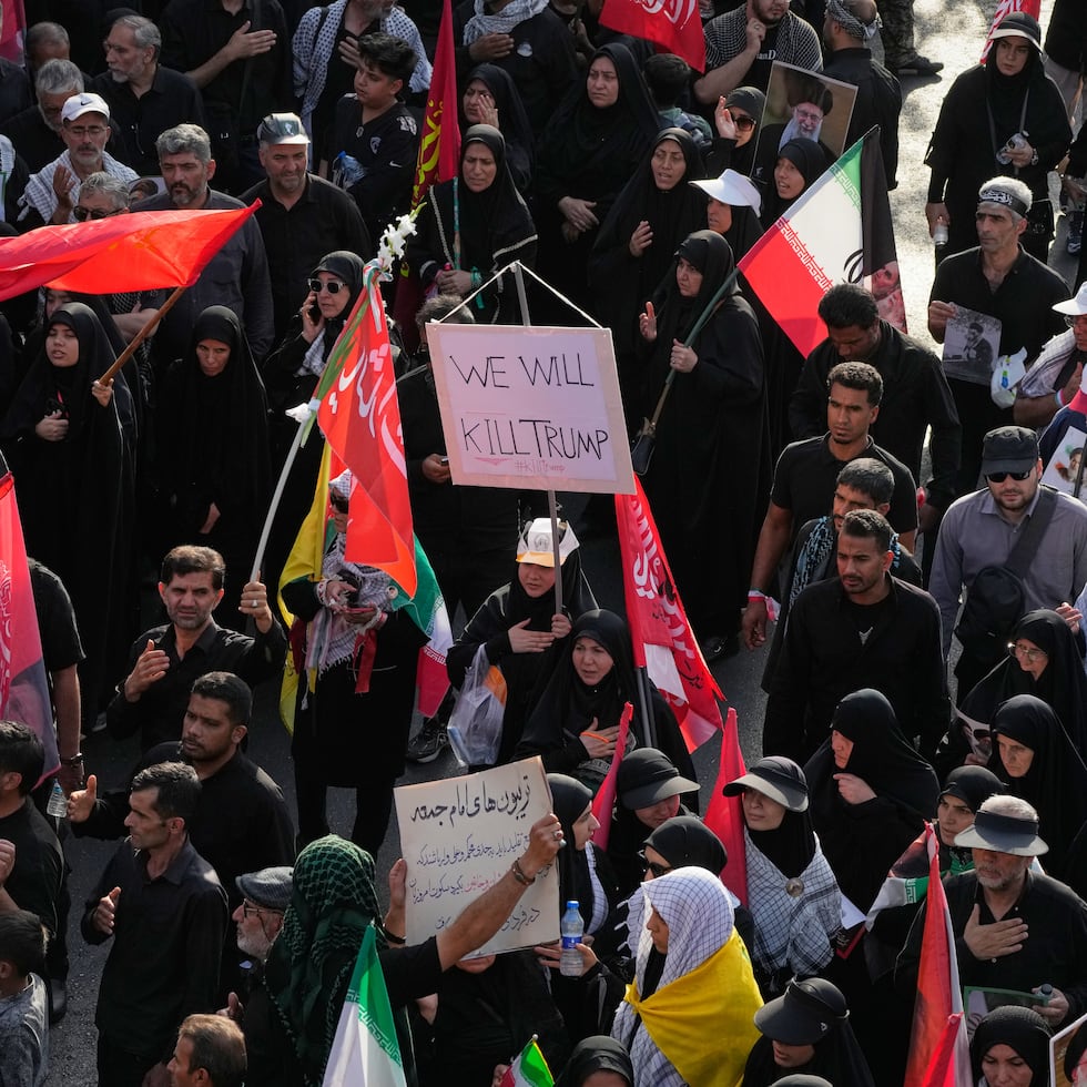 Un doliente porta un cartel que dice "Mataremos a Trump" mientras la gente se dirige a la procesión fúnebre del asesinado líder supremo iraní.