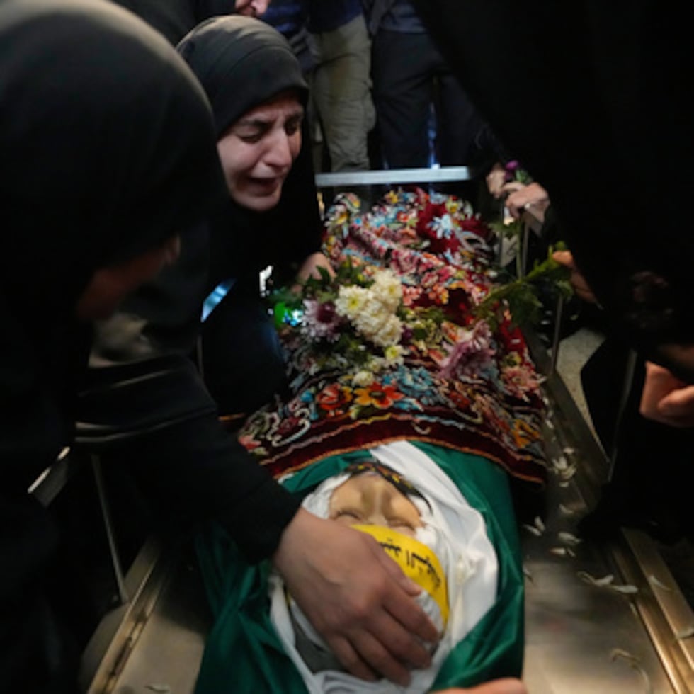 Malak Meslmani, en el centro, madre de Jawad Younes, de 11 años, asesinado en un ataque aéreo israelí, llora sobre el cuerpo de su hijo en su cortejo fúnebre en el poblado de Saksakieh.