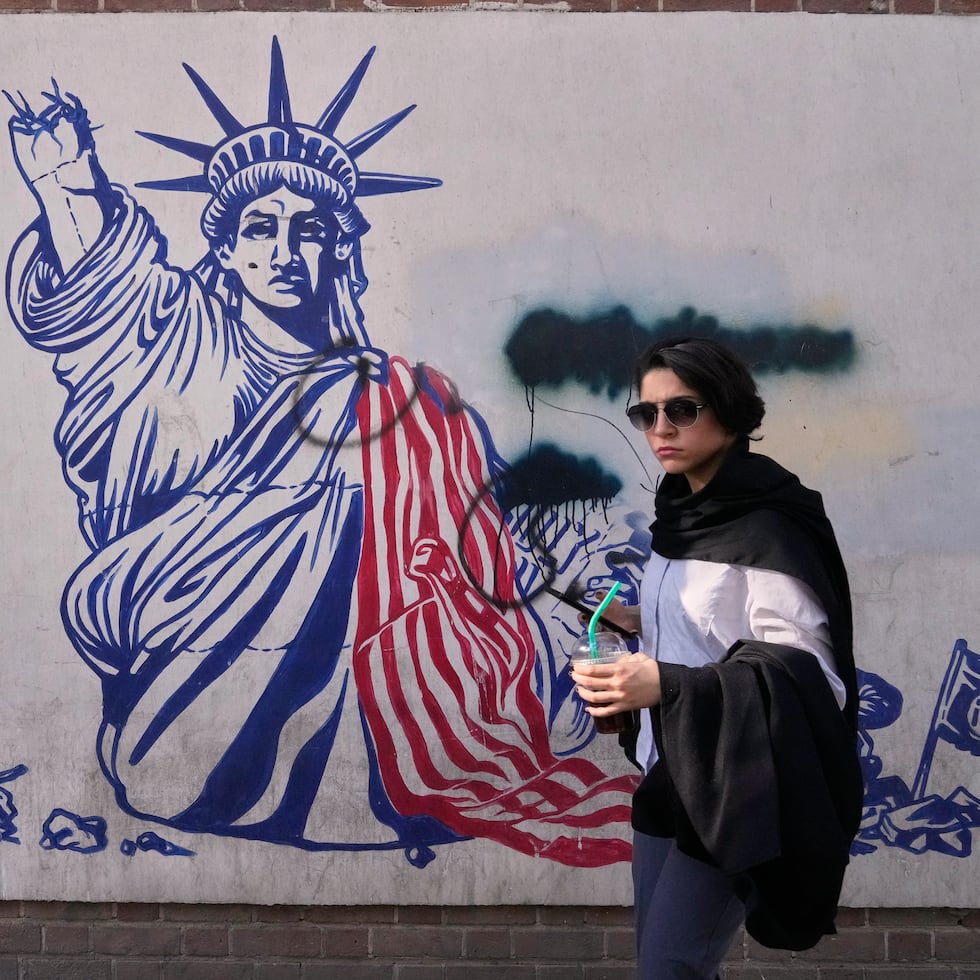 Una mujer pasa junto a un mural antiestadounidense en la pared de la antigua embajada de Estados Unidos, ahora convertida en museo, en Teherán.