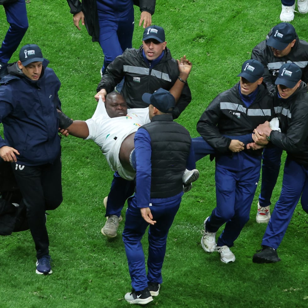 Hinchas de Senegal son sacados de la cancha durante la final de la Copa Africana de Naciones contra Marruecos el domingo.