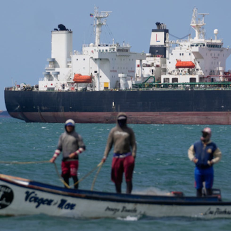 Pescadores pasan junto a un petrolero en el Golfo de Venezuela.