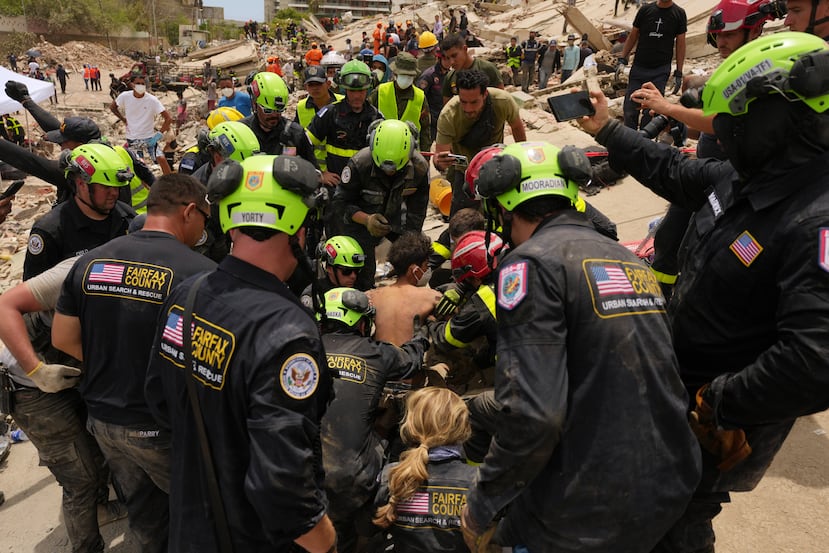 Bomberos estadounidenses del equipo de búsqueda y rescate del condado de Fairfax sacan a un niño de entre los escombros tras rescatarlo a él y a su padre de un edificio que colapsó durante los terremotos en La Guaira, Venezuela, el domingo 28 de junio de 2026. (Foto AP/Matias Delacroix)