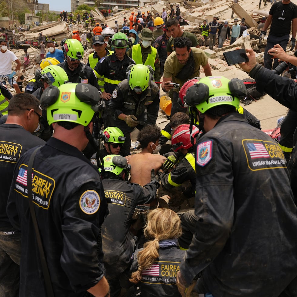 U.S. firefighters from Fairfax County search and rescue team pull a boy from the rubble after rescuing him and his father from a building that collapsed in the earthquakes in La Guaira, Venezuela, Sunday, June 28, 2026. (AP Photo/Matias Delacroix)