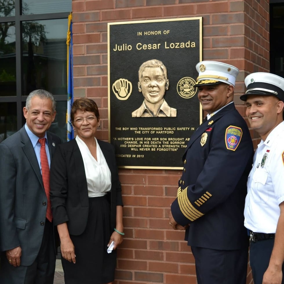 From right to left, Puerto Rican Mario Oquendo, Jr., current district chief of the Hartford Fire Department; Edward Casares, the first Puerto Rican chief of the Fire Department; and Mayra Lozada Guzmán, older sister of Julio “Julito” César Lozada Guzmán, unveil the plaque dedicated to the boy at the city’s Public Safety Complex in 2013. They are joined by retired Fire Chief Carlos M. Huertas and former city mayor Pedro Segarra.