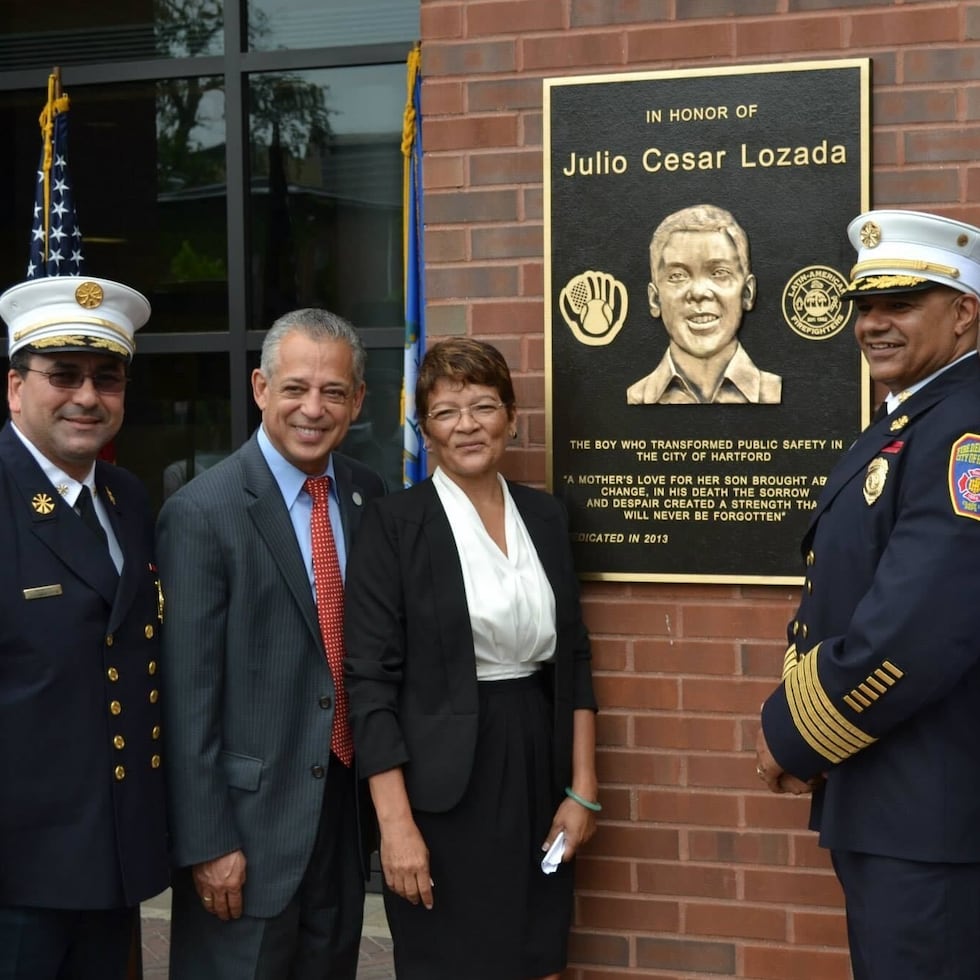 De derecha a izquierda el boricua Mario Oqueno, actual jefe de distrito del Departamento de Bomberos de Hartford; Edward Casares, primer jefe puertorriqueño del Departamento de Bomberos y Mayra Lozada Guzmán, hermana mayor de Julio "Julito" César Lozada Guzmán, inaugurando la placa dedicada al menor en el Complejo de Seguridad Pública de la ciudad en 2013. Le acompañan el jefe retirado de los Bomberos Carlos M. Huertas y el exalcalde de la ciudad Pedro Segarra.