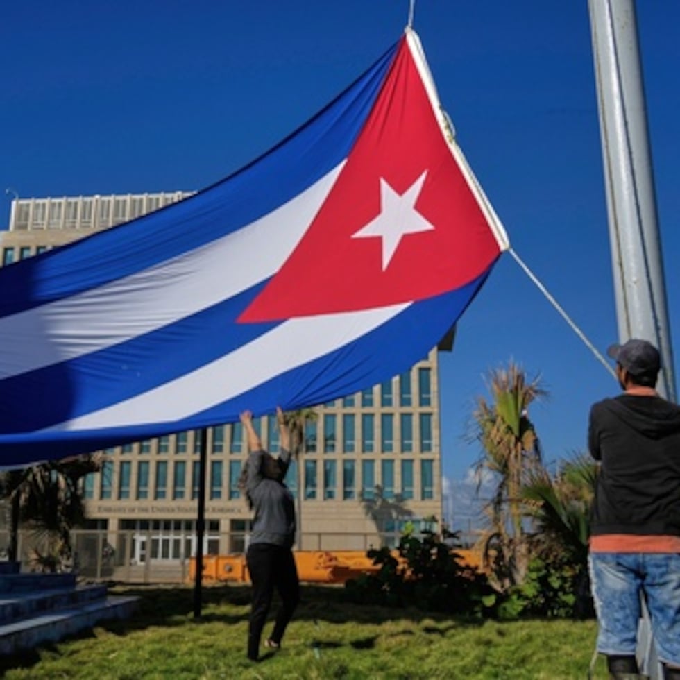 Trabajadores ondean la bandera cubana a media asta en la Tribuna Antiimperialista, cerca de la embajada de Estados Unidos en La Habana, Cuba, el lunes 5 de enero de 2026, en memoria de los cubanos fallecidos dos días antes en Caracas, Venezuela.