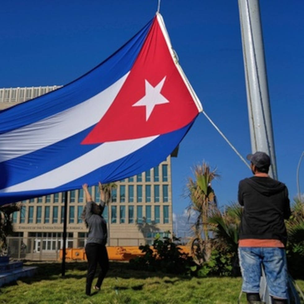 Trabajadores ondean la bandera cubana a media asta en la Tribuna Antiimperialista, cerca de la embajada de Estados Unidos en La Habana, Cuba, el lunes 5 de enero de 2026, en memoria de los cubanos fallecidos dos días antes en Caracas, Venezuela, durante la captura del presidente venezolano Nicolás Maduro por fuerzas estadounidenses. (Foto AP/Ramón Espinosa)