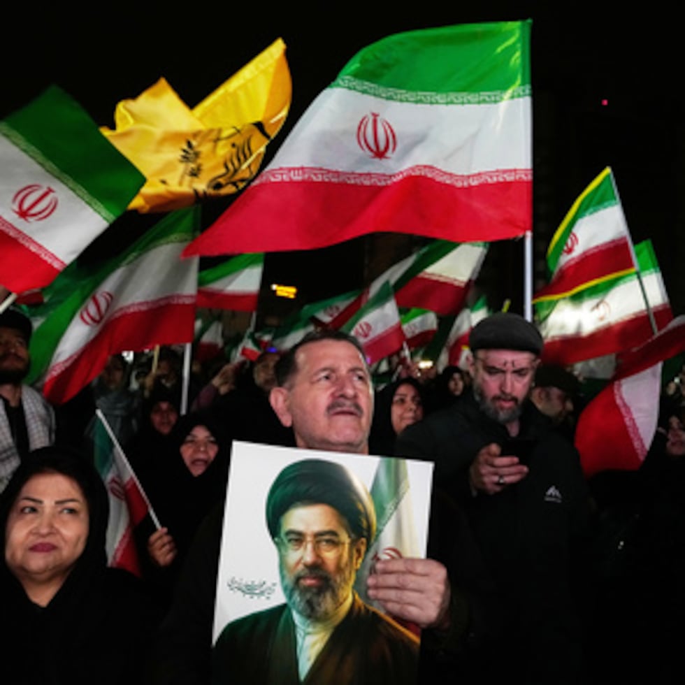 Manifestantes progubernamentales ondean banderas iraníes mientras uno sostiene una imagen del líder supremo, el ayatolá Mojtaba Jamenei, durante un acto en una plaza en el oeste de Teherán.