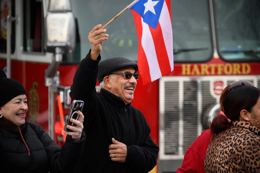 Edwin Acosta, with his wife Ada (left), greet the Three Kings Day Parade as it enters Pope Park. “We always wait for this day, the Three Kings Day, because this is the real Christmas — la verdadera Navidad,” Acosta said.