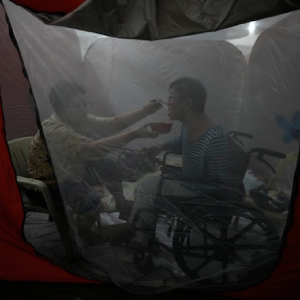 Judy Bertuso, left, feeds her husband Apollo inside a tent at an evacuation center as Typhoon Fung-wong enters the country on Sunday, Nov. 9, 2025 in Quezon city, Philippines. (AP Photo/Aaron Favila)
