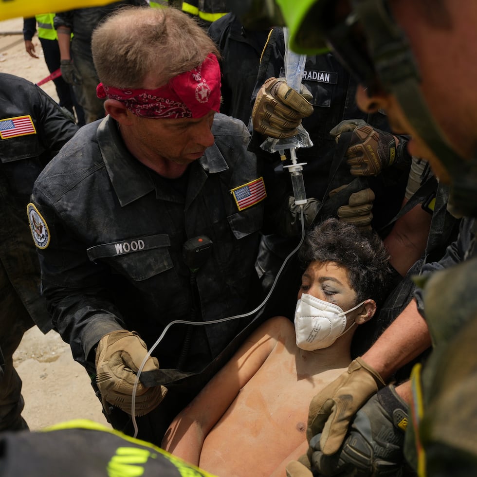 Bomberos estadounidenses del equipo de búsqueda y rescate del condado de Fairfax sacan a un niño de entre los escombros tras rescatarlo a él y a su padre de un edificio que se derrumbó durante los terremotos en La Guaira.