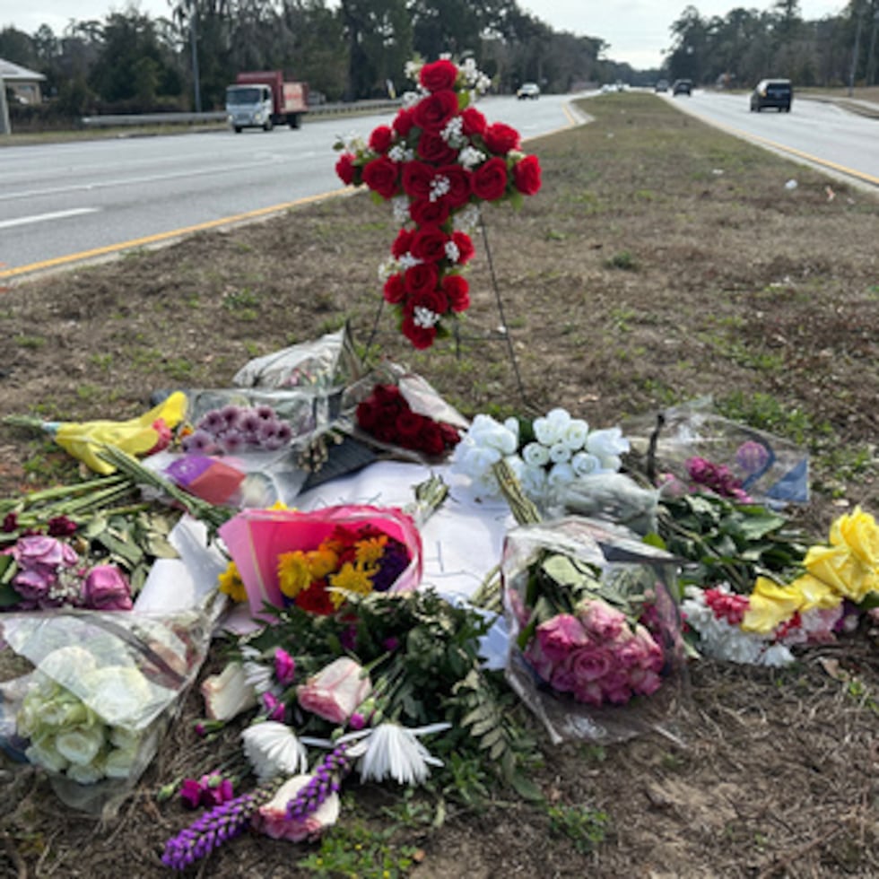 Flores dejadas en memoria de Linda Davis yacen junto a la calzada el jueves 19 de febrero de 2026, en el lugar a las afueras de Savannah, Georgia, donde Davis murió en un accidente. (AP Photo/Russ Bynum)