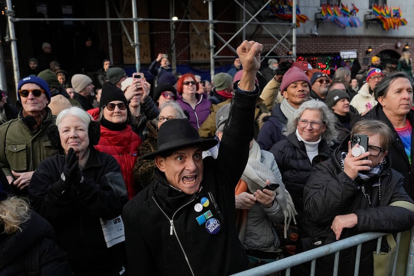 La gente reacciona frente al Stonewall Inn mientras políticos y activistas neoyorquinos izan una bandera arcoíris en un asta en el Parque Christopher, al otro lado de la calle, el jueves 12 de febrero de 2026, en Nueva York, pocos días después de que el Servicio de Parques Nacionales la retirara para cumplir con las directrices de la administración Trump. (Foto AP/Yuki Iwamura)