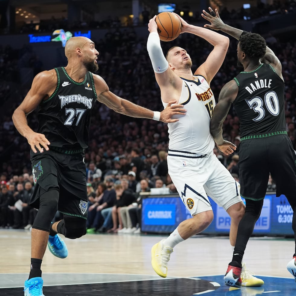 Nikola Jokics, de los Nuggets de Denver, intenta avanzar hacia la canasta mientras Rudy Gobert (izquieda) intenta detenerlo con la ayuda del alero Julius Randle (30).