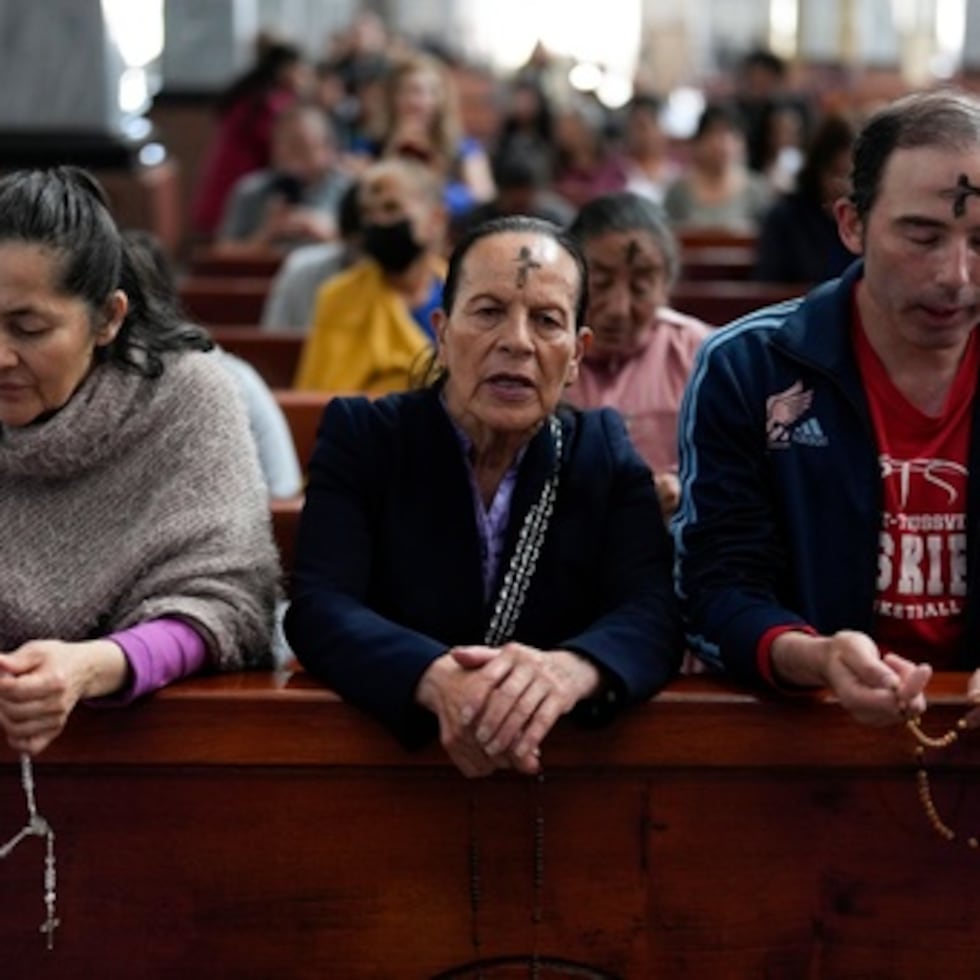 ARCHIVO - Católicos rezan el rosario mientras un sacerdote marca la frente de las personas con ceniza durante la misa del Miércoles de Ceniza en la Iglesia del Divino Niño en Bogotá, Colombia, el miércoles 14 de febrero de 2024. (AP Photo/Fernando Vergara, Archivo)