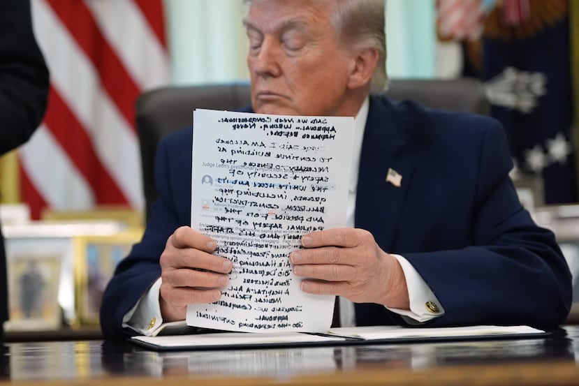 President Donald Trump holds papers in the Oval Office of the White House before signing an executive order Tuesday, March 31, 2026, in Washington. (AP Photo/Alex Brandon)