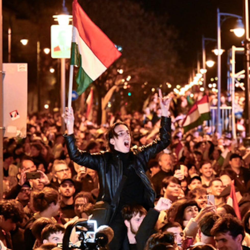 Un hombre ondea una bandera húngara mientras celebra en la calle tras el anuncio de los resultados parciales de las elecciones parlamentarias húngaras en Budapest.
