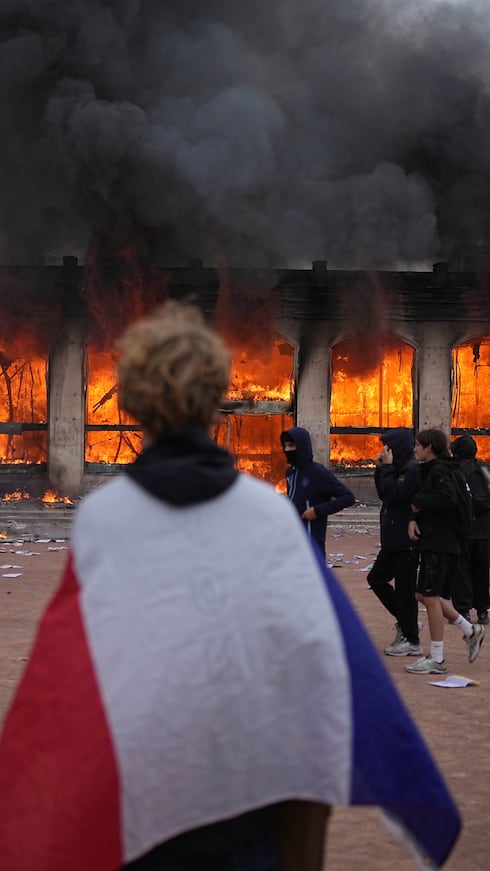 Un manifestante se envolvió en una bandera francesa frente a la oficina de turismo en llamas.