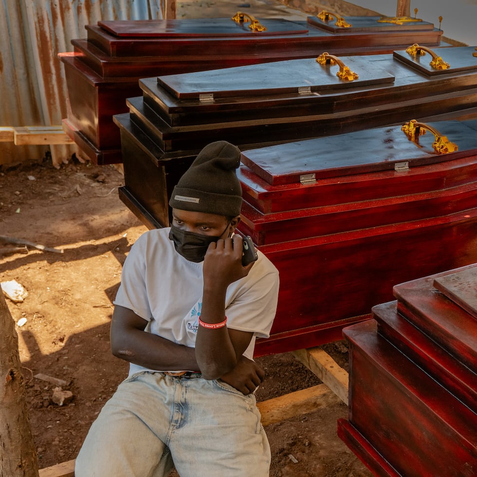 Djakisa Christian, de 18 años, gerente de una funeraria, se sienta frente a varios ataúdes a la venta