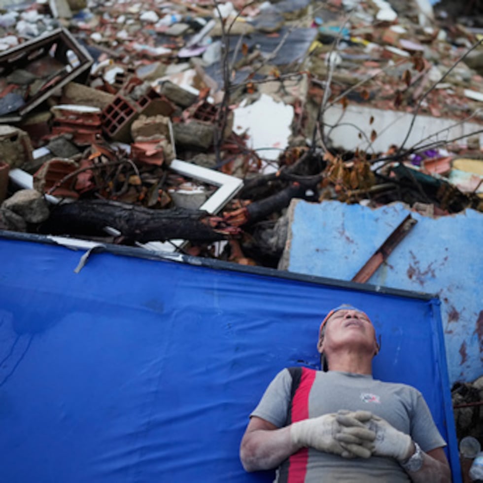 La venezolana Kerli Faria se toma un respiro entre los escombros mientras busca a sus sobrinos en un edificio que se derrumbó durante los terremotos que sacudieron La Guaira.