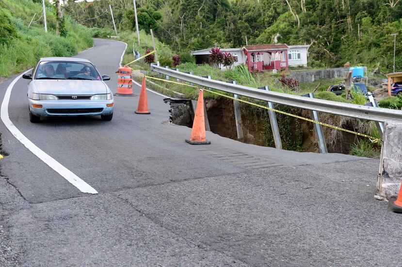Un auto pasa cerca del agujero provocado por un desprendimiento  en la carretera 905 del barrio Ingenio en Yabucoa.