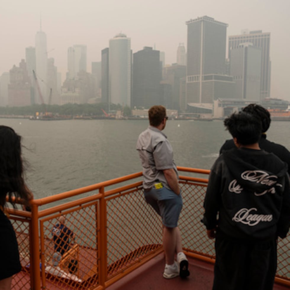 Varias personas toman el ferry de Staten Island mientras el humo de los incendios forestales cubre el cielo.
