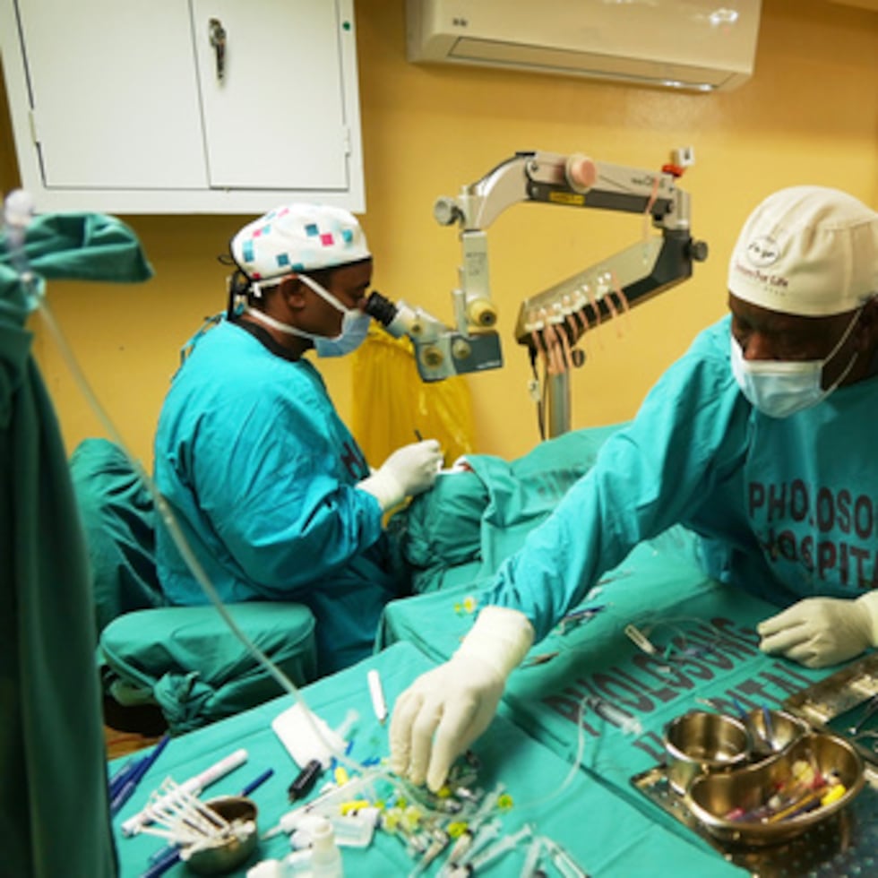Un oftalmólogo realiza una operación de cataratas mientras un asistente le entrega instrumentos quirúrgicos durante un maratón, en Tsakane, Sudáfrica, el sábado 28 de marzo de 2026.
