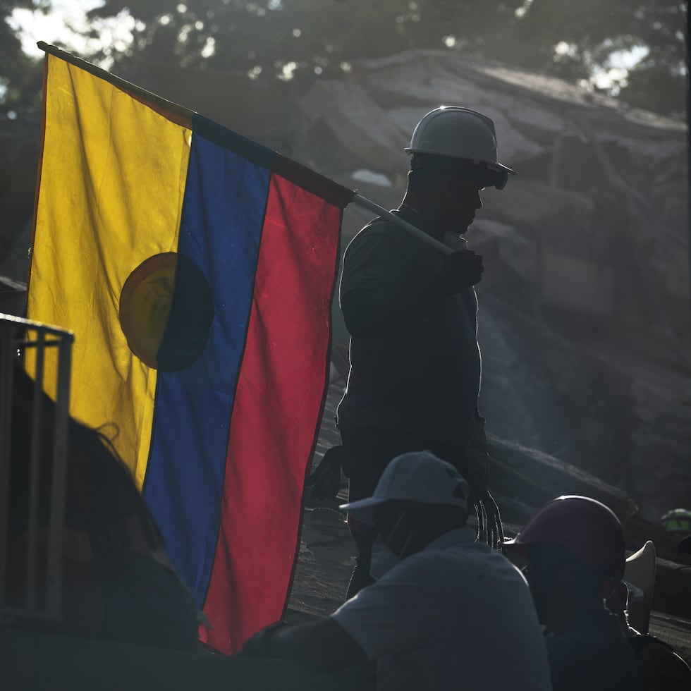 Un bombero que participa en las labores de rescate sostiene una bandera colombiana entre los escombros tres días después del terremoto que azotó Cali, Colombia.