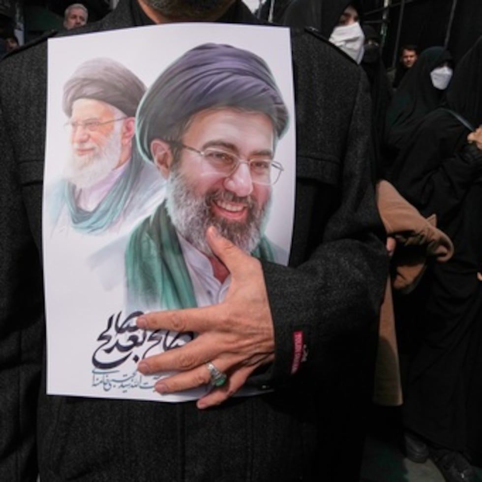 ARCHIVO - Un doliente sostiene un cartel con la imagen del ayatolá Mojtaba Jamenei, a la derecha, sucesor de su difunto padre, el ayatolá Ali Jamenei, a la izquierda, como líder supremo, durante el cortejo fúnebre por los altos cargos militares y civiles iraníes muertos durante la campaña entre Estados Unidos e Israel en Teherán, Irán, el 11 de marzo de 2026. (AP Photo/Vahid Salemi, Archivo)