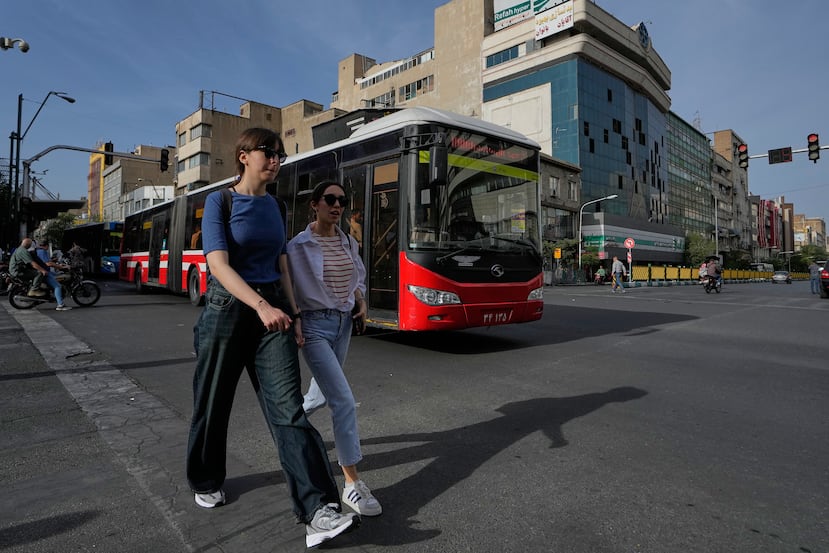 Mujeres caminan mientras un autobús público pasa por una intersección en el centro de Teherán, Irán, el jueves 28 de mayo de 2026. (Foto AP/Vahid Salemi)