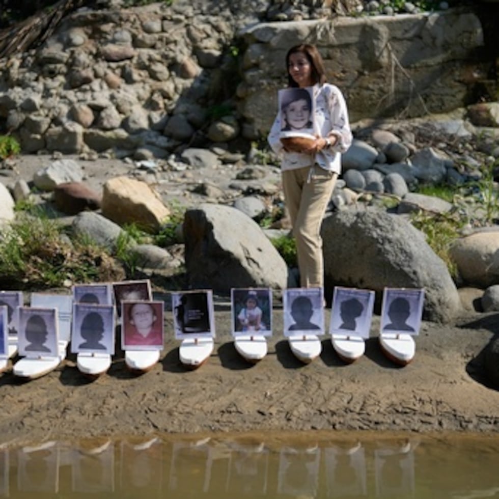 Martha Lucía López sostiene un barco con una foto de su hijo Sergio Melendro López, desaparecido desde la erupción del Nevado del Ruiz, antes de la suelta de pequeños barcos con fotos de los niños desaparecidos en el río Gualí, en Honda, Colombia. (AP Photo/Fernando Vergara)