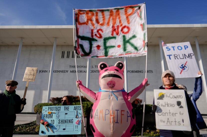 ARCHIVO - Manifestantes, entre ellos Nadine Siler, de Waldorf (Maryland), ataviada con un disfraz de rana rosa, sostienen pancartas en un punto de protesta designado frente al Centro John F. Kennedy para las Artes Escénicas, un día después de que una junta nombrada por Trump votara a favor de añadir el nombre del presidente Donald Trump al Centro Kennedy, el 20 de diciembre de 2025, en Washington. (Foto AP/Julia Demaree Nikhinson, archivo)