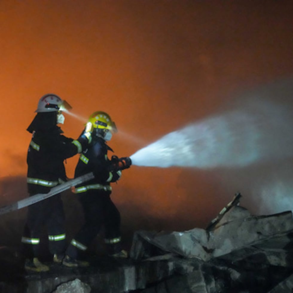En esta fotografía difundida por la agencia de noticias Xinhua, se ve a bomberos trabajando para extinguir un incendio.