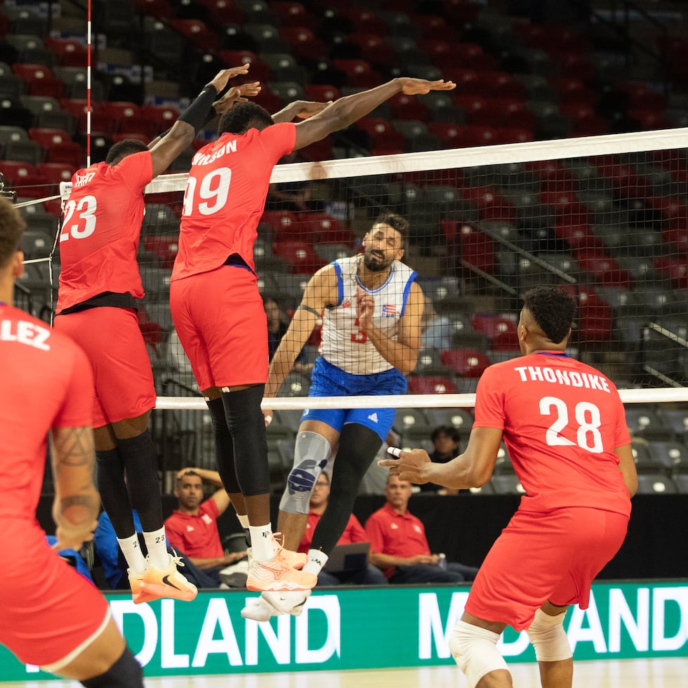 Jair Santiago, de Puerto Rico, ataca ante el doble bloqueo de Cuba durante el partido de cuartos de final del Campeonato Norceca, este lunes en Canadá.