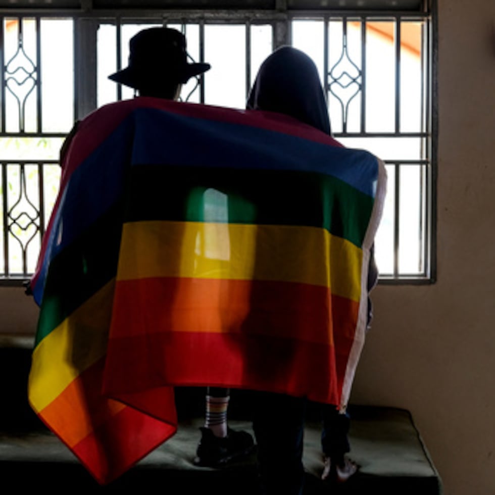 Una pareja gay ugandesa se cubre con una bandera del orgullo.