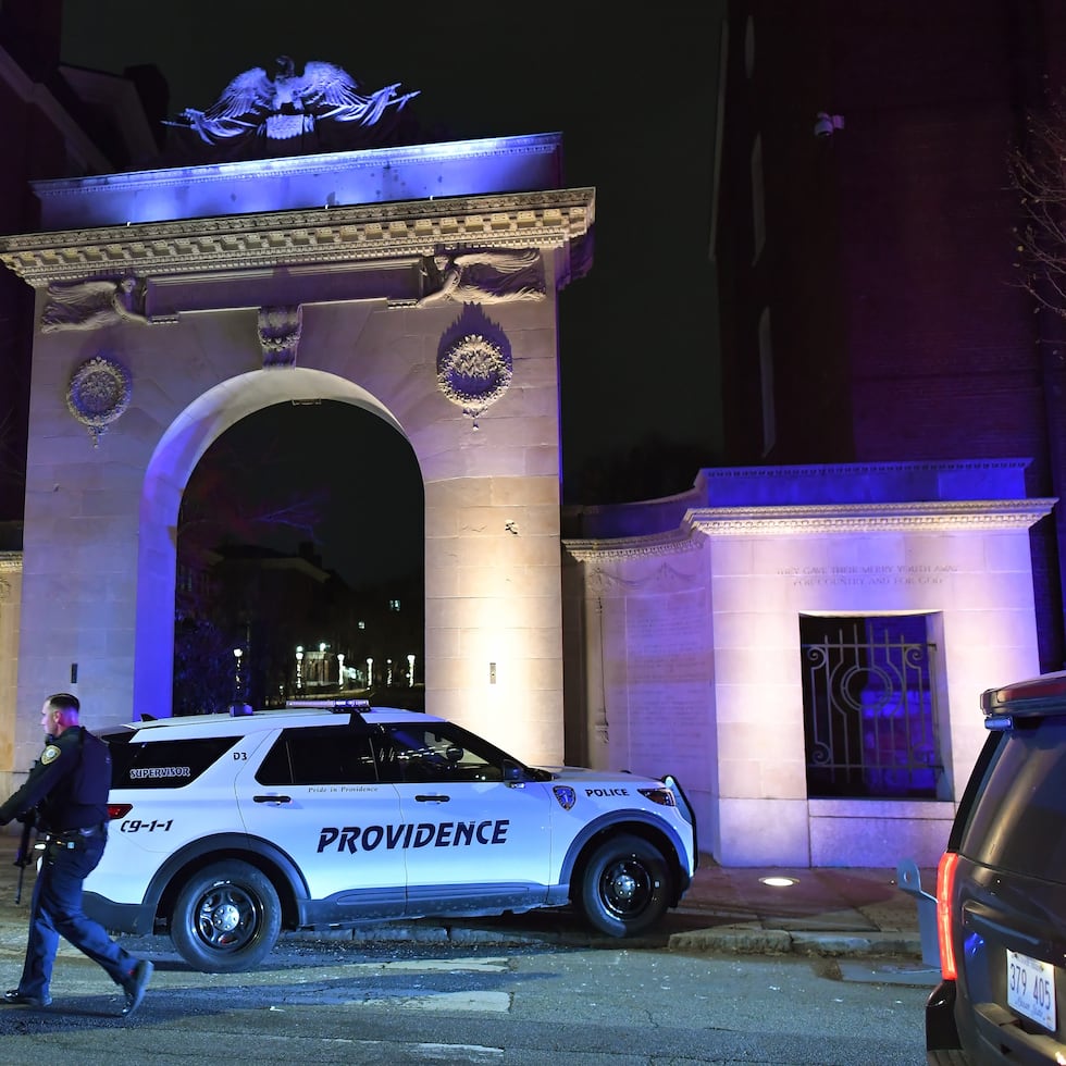 Law enforcement officials walk near an entrance to Brown University in Providence, R.I., on Saturday, Dec. 13, 2025, during the investigation of a shooting. (AP Photo/Steven Senne)