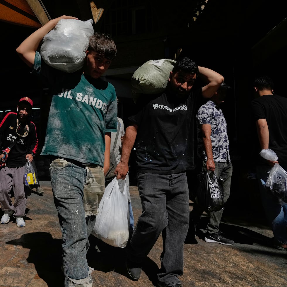 Dos personas cargan paquetes en el histórico Gran Bazar de Teherán, Irán