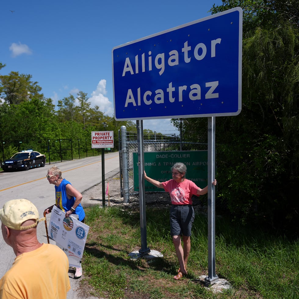 Personas se toman fotos delante de un cartel que dice "Alcatraz de los caimanes" en la entrada de una cárcel para inmigrantes en los Everglades de Florida.