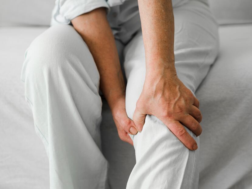 Mujer se toca rodilla adolorida