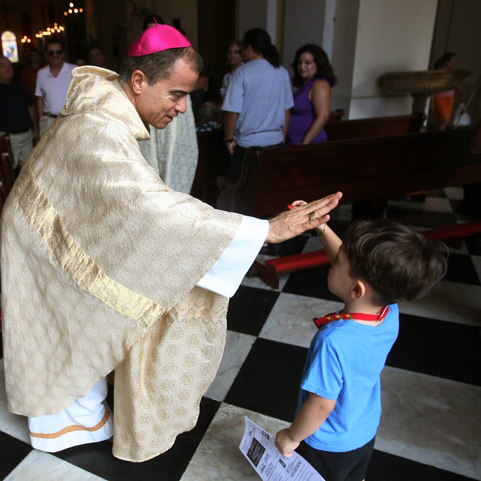El arzobispo de San Juan, Roberto Gonzalez Nieves, choca la mano de un niño tras una misa de aguinaldo, en la catedral de la capital.