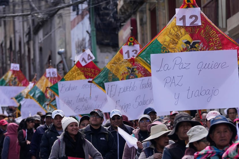 Vendors hold signs reading in Spanish, "La Paz wants peace and work," during a march against protesters who were blocking access to the city, in La Paz, Bolivia, Tuesday, May 26, 2026. (AP Photo/Juan Karita)